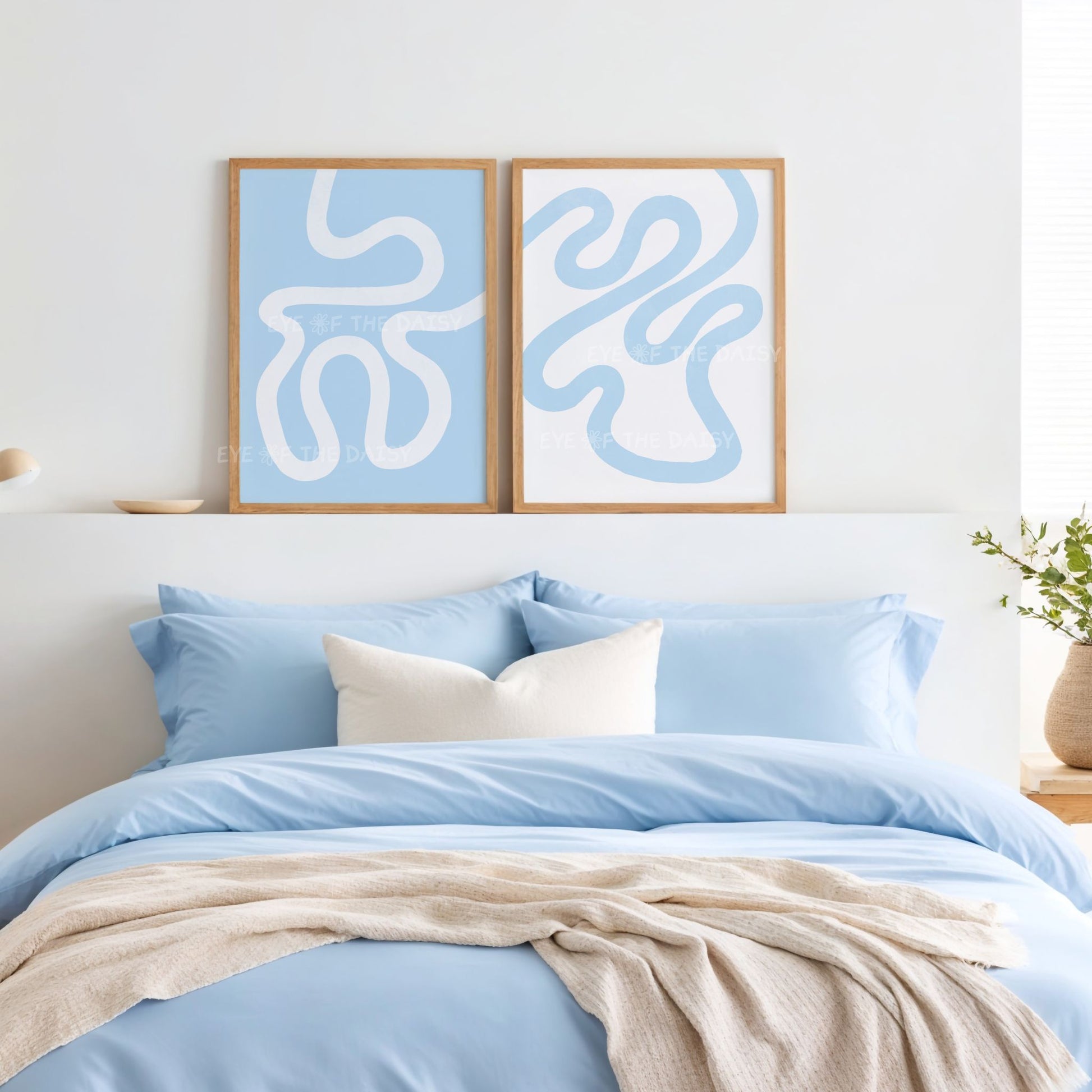 Set of two modern sky blue printable wall art prints of an abstract scribble line drawing, displayed above a bed in a bedroom