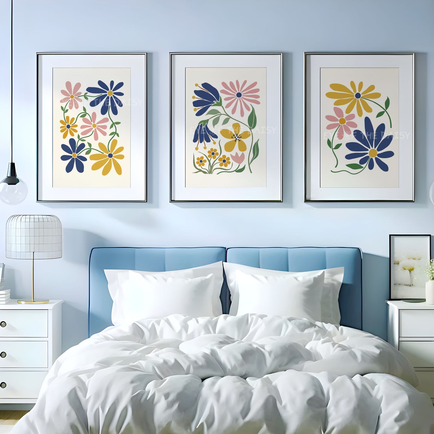 Three abstract botanical wall art prints with mustard yellow, navy blue and blush pink flowers on beige background above a bed
