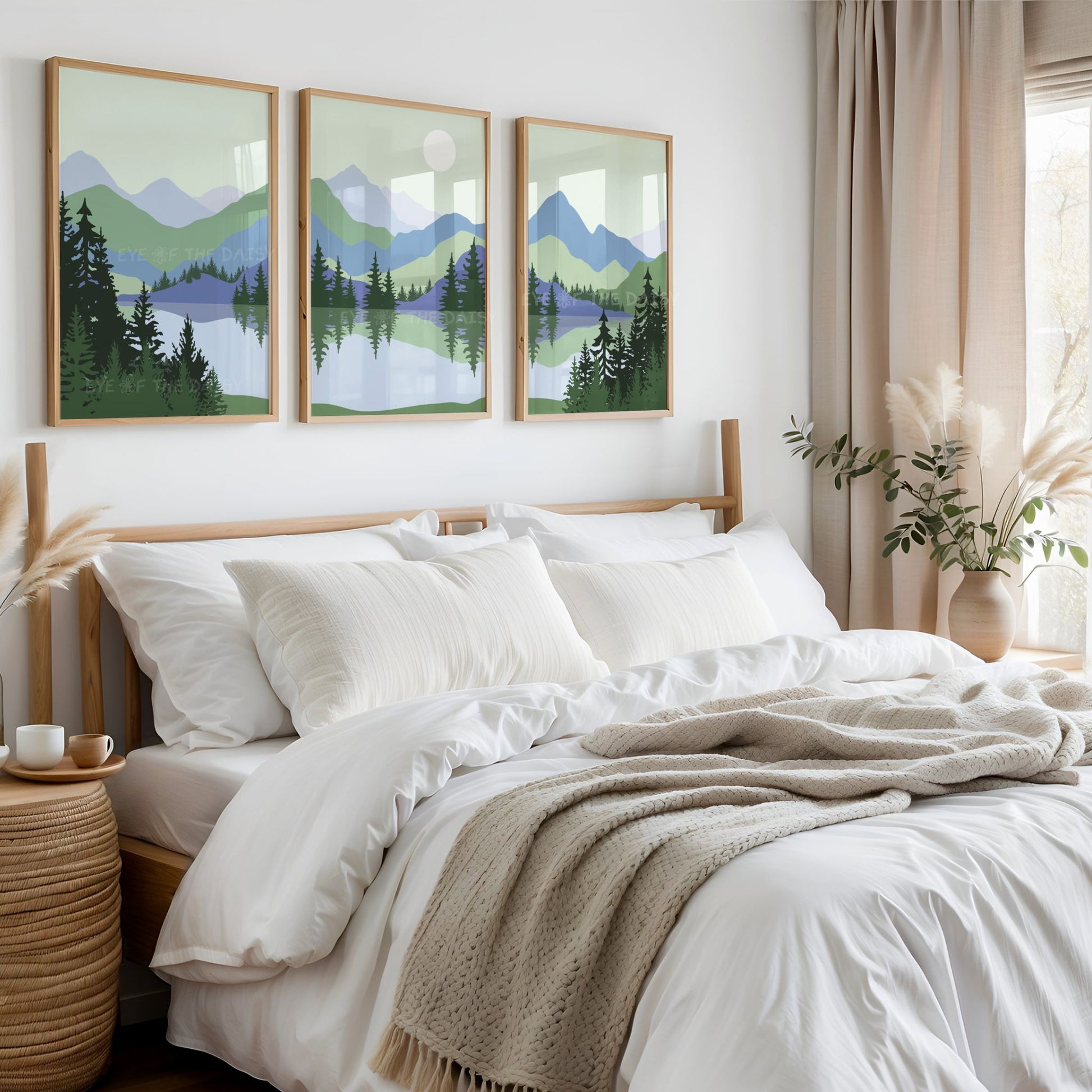 Three piece printable wall art set of sage green & blue abstract mountain landscape scenery in a continuous style, with lake & trees, above a bed in a boho bedroom