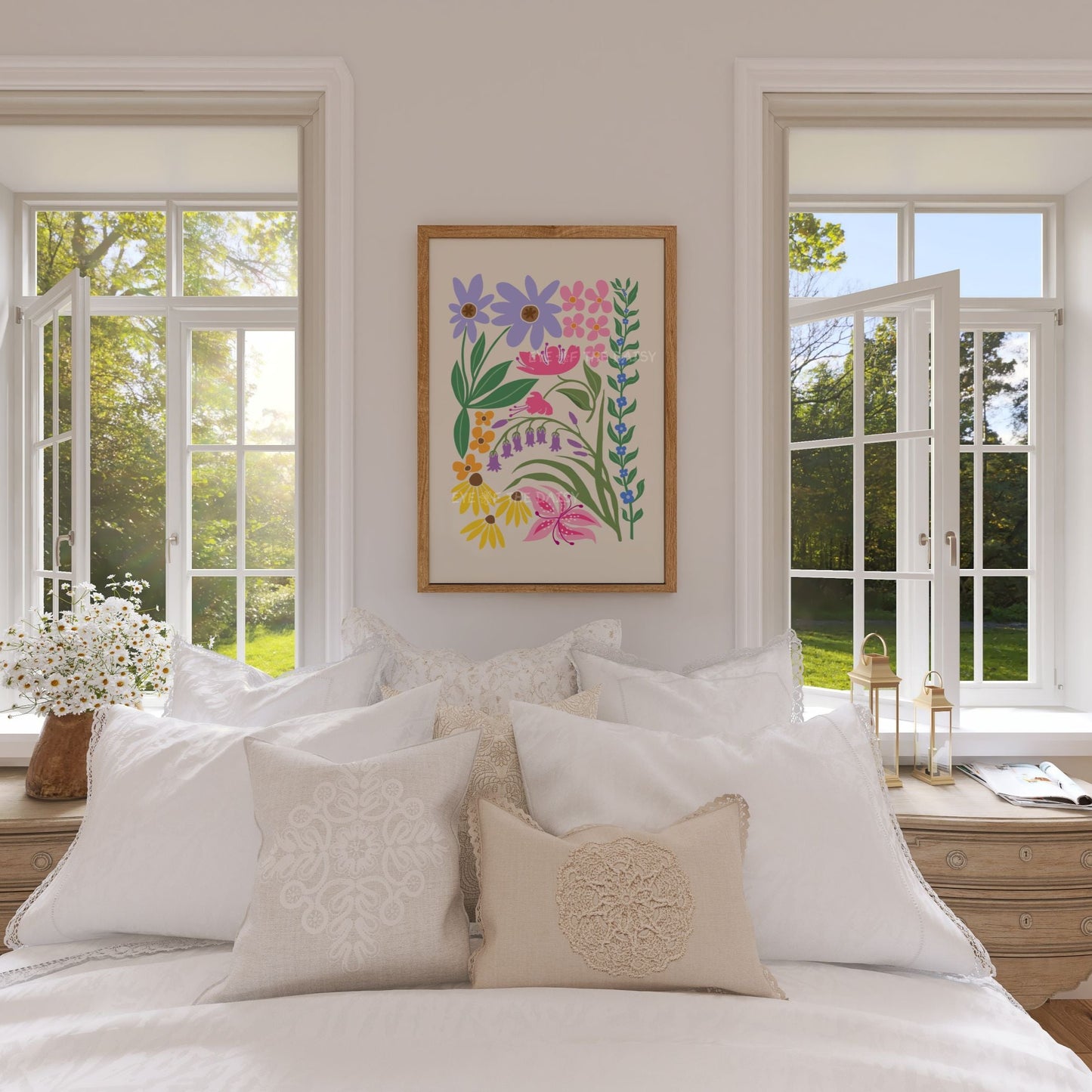 Colourful floral abstract print of vibrant flowers and leaves in pink, lilac, orange and yellow framed on a wall in a country cottage bedroom above a bed with pillows